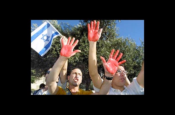 Israeli right-wing student activists hold up their hands, painted in red as a symbol of bloodshed