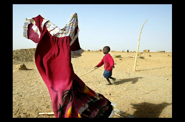 a sudanese refugee plays outside his tent in the tine-chad camp