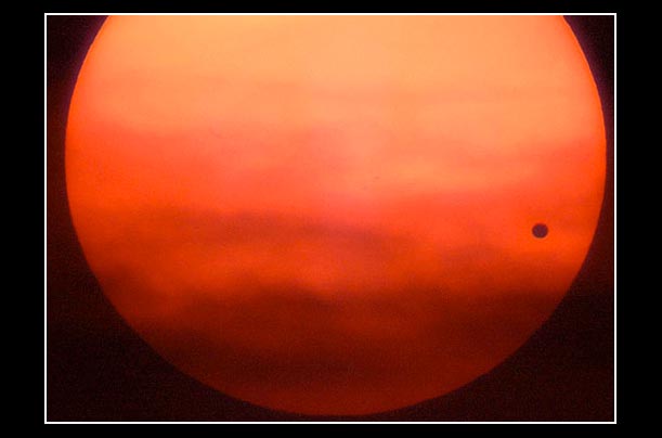 The planet Venus appears as a black dot against the surface of the sun rising over Chesapeake Bay
