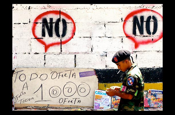 venezuelan military officer in caracas walks past a painted graffiti wall