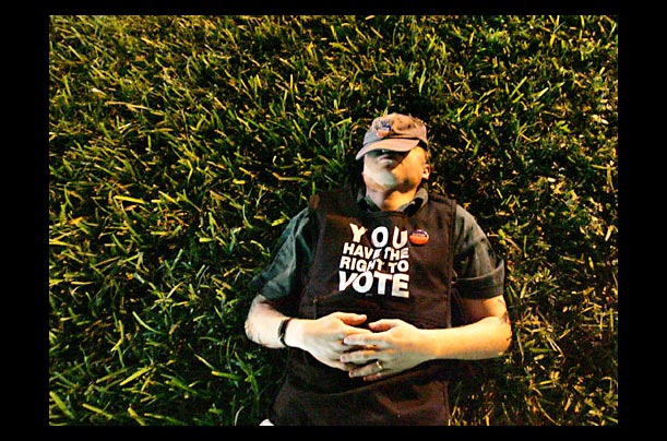 A Election Protection volunteer naps in the grass after nightfall outside a precinct in Broward County in Fort Lauderdale, Floria