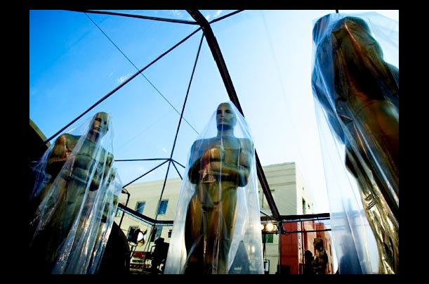 Oscar statues stand with plastic covers during preparations for the 77th Annual Academy Awards