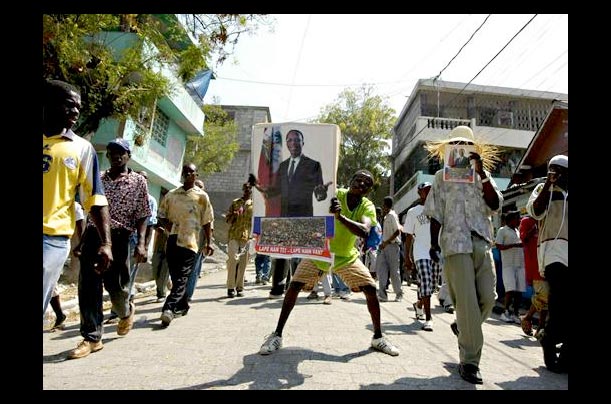 Haitian protesters, led by Reverend Gerard Lean Juste, one of the most loyal supporters of  parade down the streets of Port-au-Prince on the one-year anniversary of former President Jean-Bertrand Aristide ouster