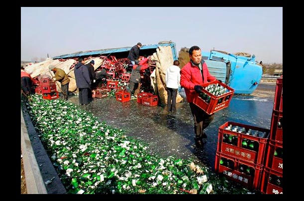 Workers salvage crates of beer from an overturned truck in Shenyang, in China's northeastern Liaoning province