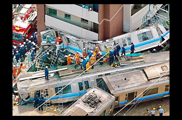 Rescue personnel work at the site of a train crash in Amagasaki, Japan, where a commuter train derailed and smashed into an apartment building