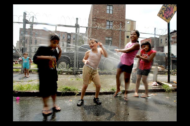 Children cool off with an open fire hydrant in Williamsburg, Brooklyn