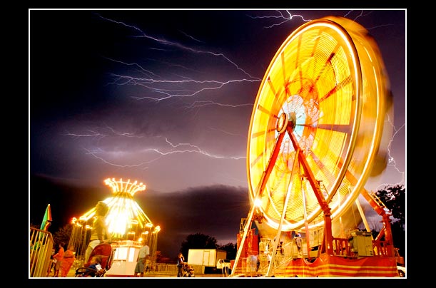 Lightning flashes behind the Ferris wheel at the Texas Oklahoma Fair in Wichita Falls, Texas,