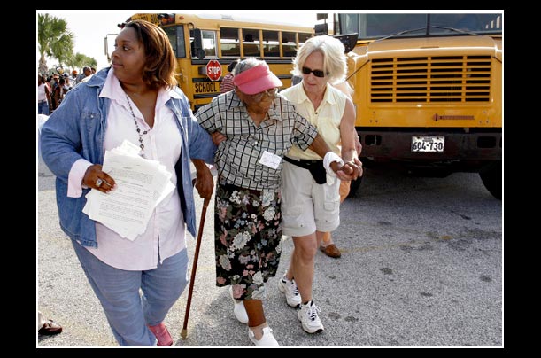 Stephanie Thomas and Marianne Cassells help Mary Jones to board an evacuation bus at the Island Community Center in Galveston, Texas