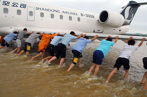 Airport workers try to move a plane out of the water at an airport in China's Shandong province.
