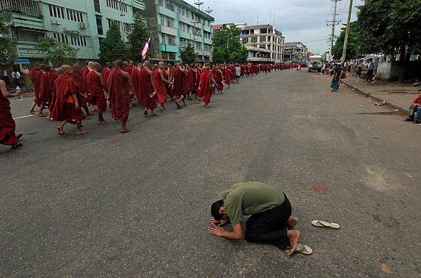 A man prays toward a column of Buddhist monks in Rangoon, Burma.  The monks have been marching through the streets of the city, calling for the overthrow of the country's ruling junta.

