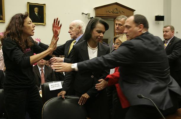 Security agents rush to protect Secretary of State Condoleezza Rice, arriving to testify on Capitol Hill, as she was confronted by a protester with painted hands.
