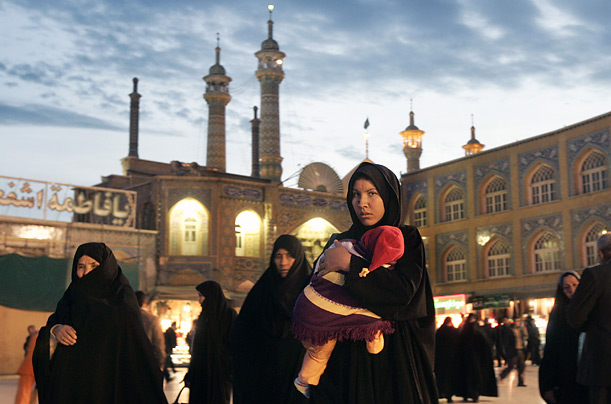 A woman carries her child past Hazrat-e Masumeh, the mausoleum of Imam Reza's sister Fatemeh who died in the 9th century A.D. in the holy city of Qom, Iran.
