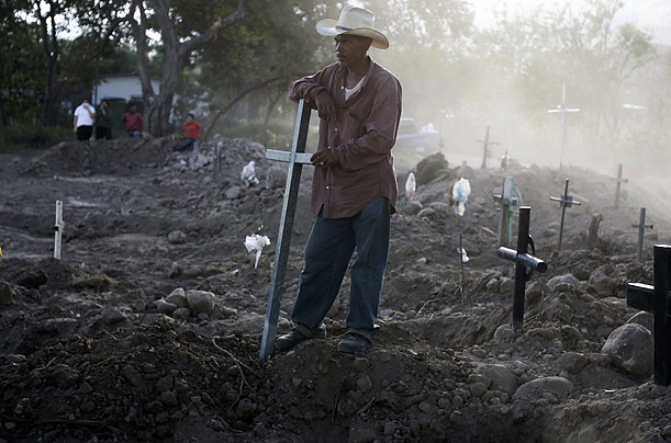 A relative stands near the graves of exhumed corpses at an Ojo de Agua cemetery north of Tegucigalpa, Honduras. The expansion of a road in central Honduras forced the relocation of over 150 bodies.