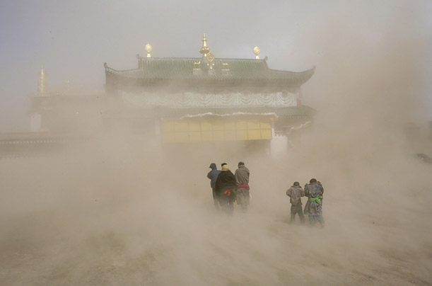 Ethnic Tibetan worshippers enter a monastery to celebrate Monlam, one of the most important religious event in Tibetan Buddhism, during a sandstorm in Aba, Sichuan province.