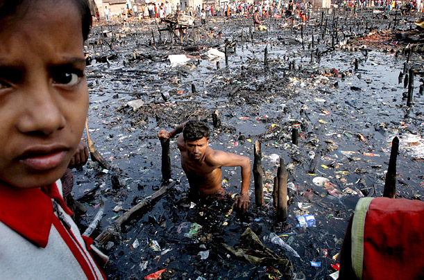 An Indian man searches for his valuables in debris and water after a fire burned down a whole locality Sunday night in Topsia, Calcutta.