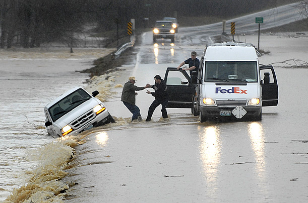 FedEx driver Jay McMullin helps Odell Bunch into his delivery truck after Bunch's Ford Ranger was swept off by floodwaters in southern Missouri.