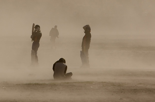Men are caught in a dust storm while playing cricket at a playground in Kabul. 

