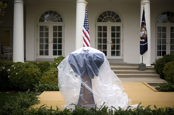 A plastic tarp covers a podium in the Rose Garden at the White House, where President Bush had planned to deliver a speech on the Colombia Free Trade Agreement.