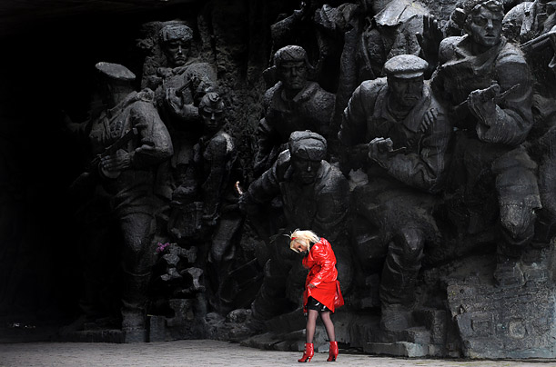 A girl straightens her overcoat as she passes one of the monuments in the open-air museum of World War II in Kiev. Ukraine, along with Russia