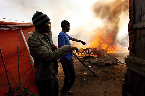 Two men attempt in vain to salvage items from a burning shack during ongoing xenophobic clashes near Johannesburg, South Africa.