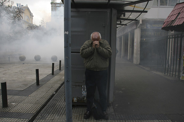 A pedestrian takes cover from teargas during a rally in Santiago, Chile, where students clashed with riot police during a protest against a proposed education reform.  
