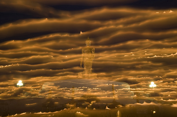 In this 25 second exposure, Thai Buddhists carry candles around a large Buddha on Asanha Puja Day near Bangkok.

