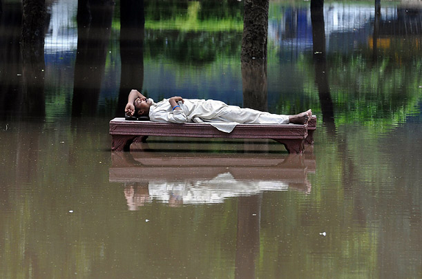 A Pakistani man rests on a bench amongst floodwater after a heavy monsoon rain in Lahore.