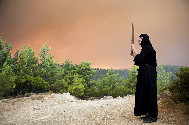 A nun from the Panagia Ypseli monastery holds a holy icon in prayer against the fire that has been ravaging the Greek island of Rhodes for the past four days.
