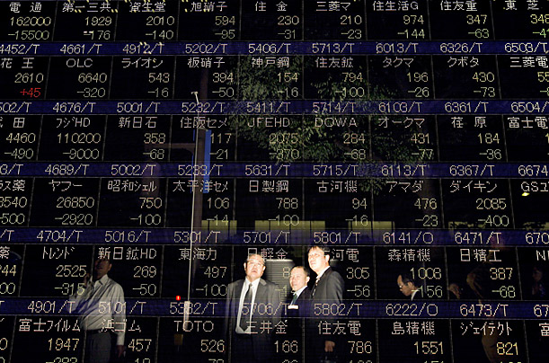 Businessmen watch stock prices drop on an indicator board in downtown Tokyo.

