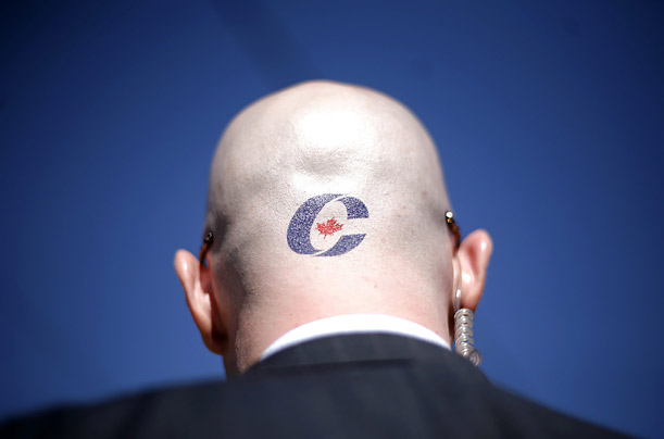 A staff member for Canadian Prime Minister Stephen Harper sports the Conservative Party logo on his head at a rally in Kitchener, Ontario.

