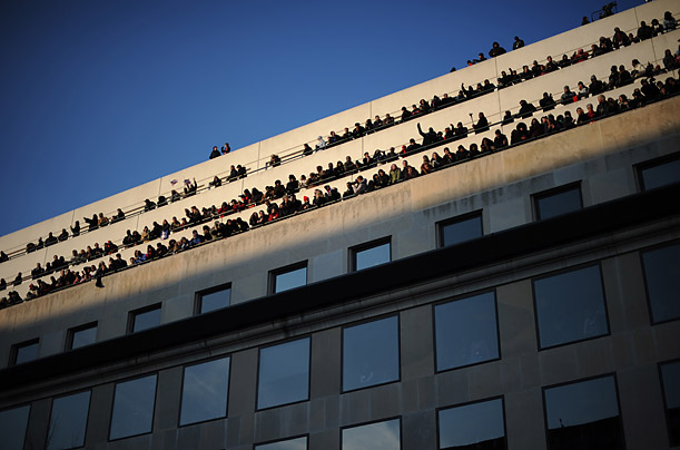 People crowd a building during the inaugural parade in Washington, DC.