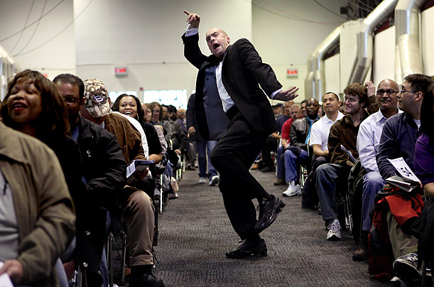 Bidders' assistant Jeff Johnston keeps the auctioneer informed of bids with arm and body motions at a foreclosed home auction at the Javits Center in New York.