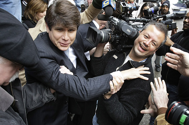 Former Illinois Gov. Rod Blagojevich holds onto a cameraman before nearly falling off a sidewalk after departing federal court in Chicago, where he was arraigned on federal racketeering and fraud charges.
