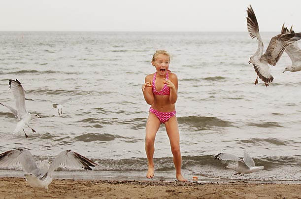 A girl screams after the cheese puff she was feeding seagulls blew away from her at Huntington Beach, Ohio.