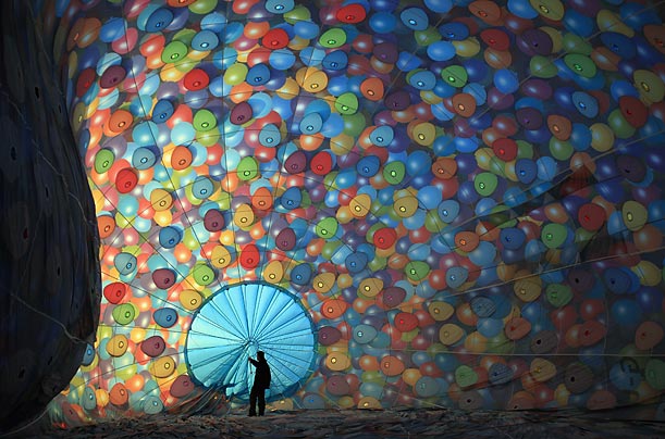 A balloonist makes the final checks on his balloon as he prepares for a 100-balloon mass take-off at dawn at the International Balloon Fiesta in Bristol, England.