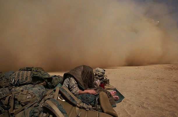 Here It Comes
U.S. Marine Elias Prado takes cover from the dust of a helicopter taking off from a forward operating campsite in Marjah, Afghanistan.