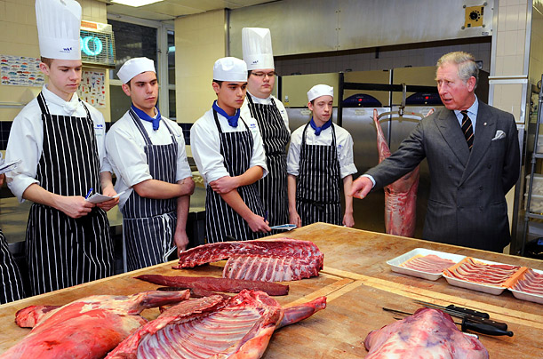 During a visit to Westminster Kingsway College in London, Prince Charles chats with catering students in a butchery class.