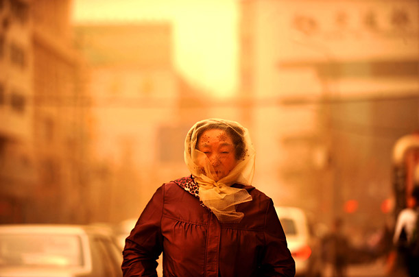 In Lanzhou, the capital of China's Gansu Province, a woman covers her face as she braves the powerful sandstorm that hit the region on Friday.