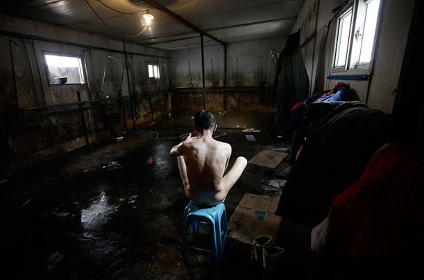 A rescue worker sits after taking a bath. He had been, working at the Wangjialing coal mine in northern China where a flood had stranded many miners.