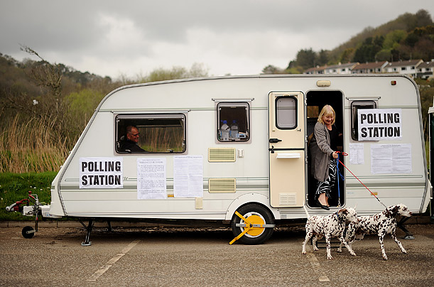 A woman leaves with her dogs after voting in a caravan turned polling station in Cornwall, England.