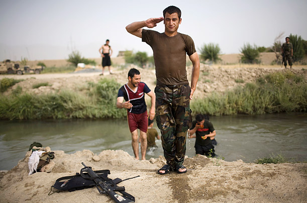 An Afghan army soldier salutes after swimming in a canal near a joint Afghan-U.S. base in Kandahar, Afghanistan.
