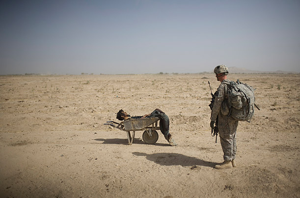 A US Army soldier looks at the body of a suspected Taliban IED placer, who was killed in a coalition missile strike in Zhari district of Kandahar province. 
