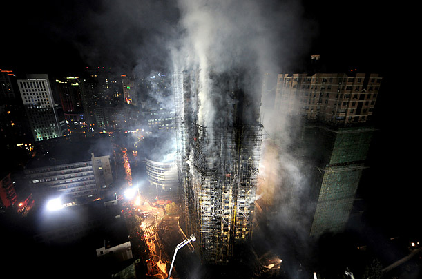 Chinese firefighters extinguish a huge fire that engulfed a high-rise in Shanghai after construction scaffolding surrounding the building caught fire and spread to the building