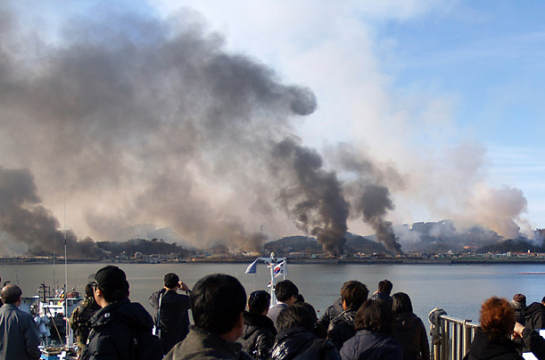 Onlookers watch as smoke rises from South Korean Yeonpyeong Island after being hit by dozens of artillery shells fired by North Korea.