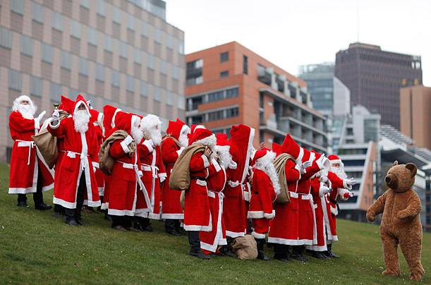 Santa Clauses receive instructions from a teddy bear and pose for pictures after a general meeting to launch the annual Student Union charitable Santa Claus rental campaign in Berlin, 
