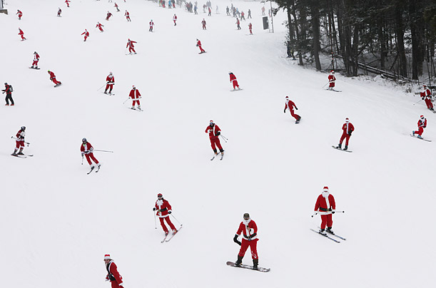Skiers and snowboarders dressed as Santa Claus head down the slope at Sunday River, Maine.
