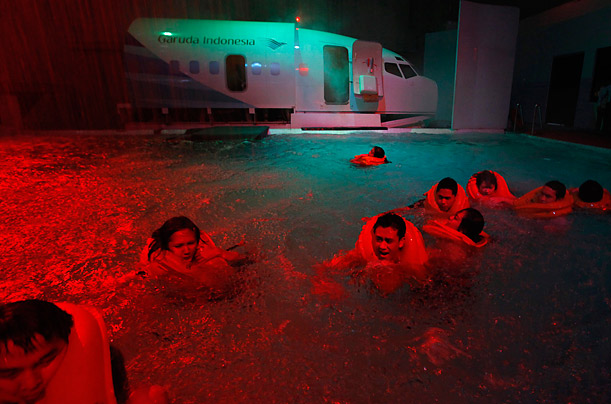 Flight attendant trainees swim during an aircraft emergency evacuation drill at Garuda Indonesia Training centre in Jakarta.