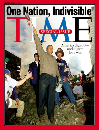 Photograph of George W. Bush waving an American flag from the rubble at Ground Zero.