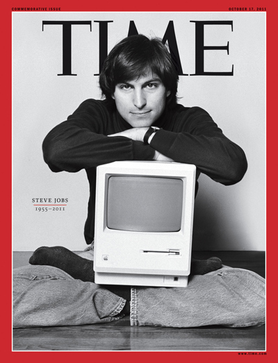A young Steve Jobs poses with a Mac computer on his lap