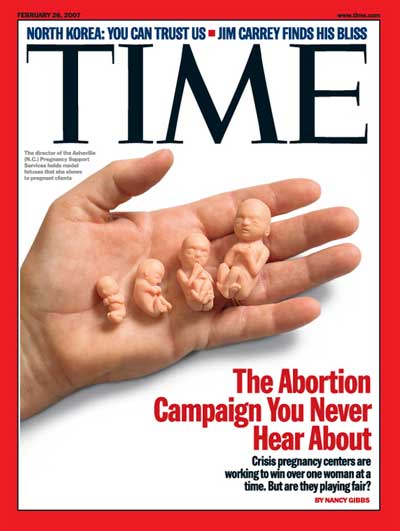 A hand holding model fetuses in the palm of its hand.